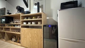 Eine Küche mit Holzausstattung, einem Kühlschrank, einer Mikrowelle und diversen Küchengeräten.