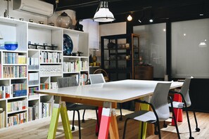 Eine moderne Bibliothek mit einem großen, weißen Tisch, zahlreichen Bücherregalen und vielfältigem Lese-Material.