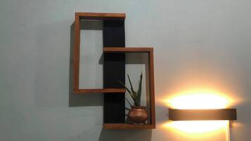 Estante de pared con una planta en maceta y un aplique.