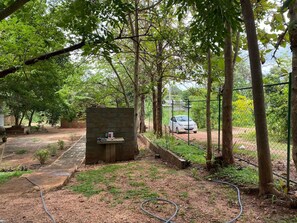 A fenced outdoor area with a concrete structure, a car, and a hose. - Ayana Eco Rest Dambulla (Dambulla)