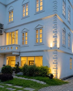 Un edificio de varios pisos con ventanas iluminadas y un jardín cuidado.