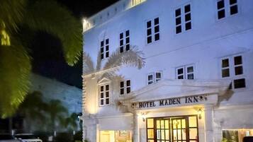 Un edificio blanco con un cartel que dice 'HOTEL MADEN INN' en la entrada.