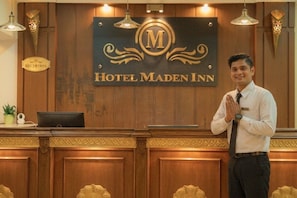 A hotel reception desk with a sign reading 'Hotel Maden Inn.'