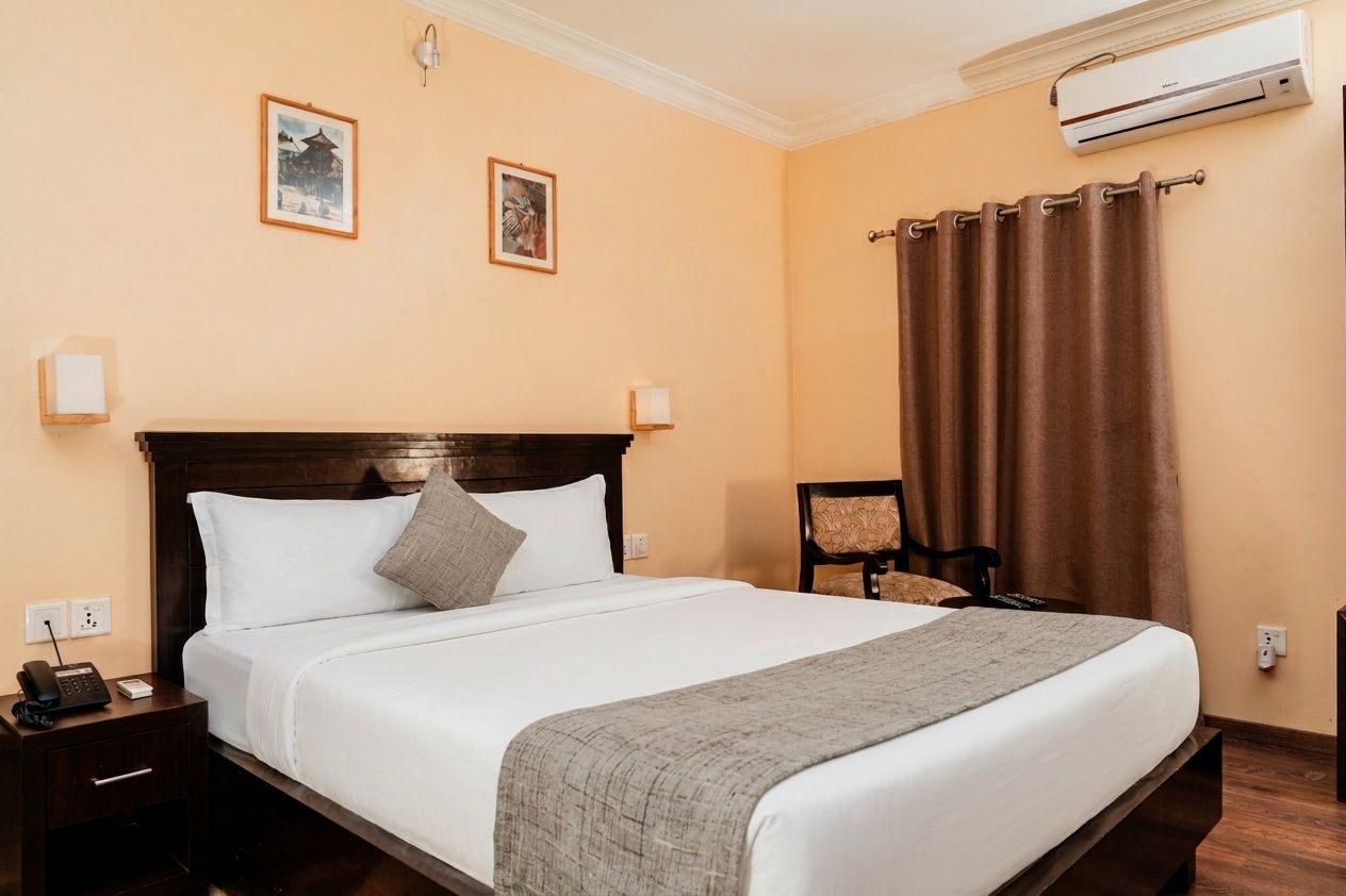Una habitación de hotel con cama, mesita de noche, lámpara y equipo de aire acondicionado.
