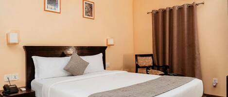 Una habitación de hotel con cama, mesita de noche, lámpara y equipo de aire acondicionado.