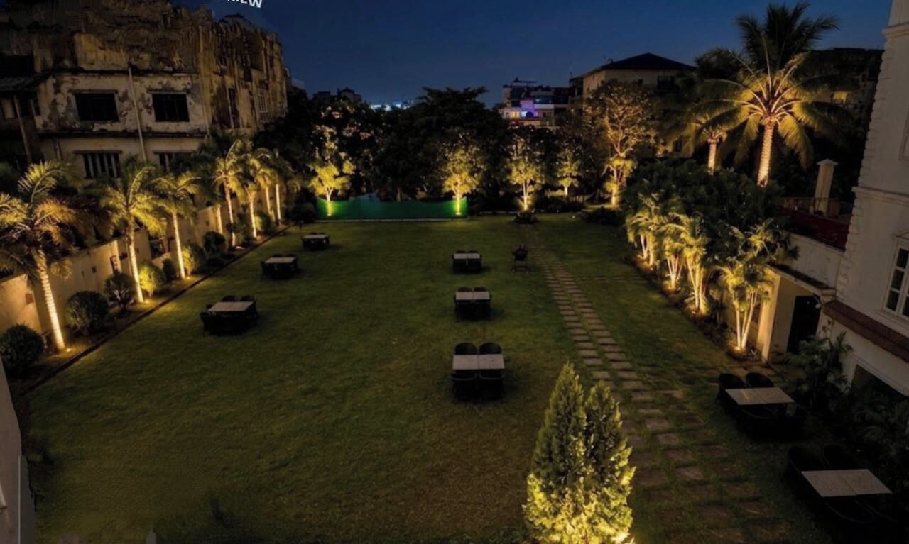 Un patio con césped, zonas de estar y palmeras.