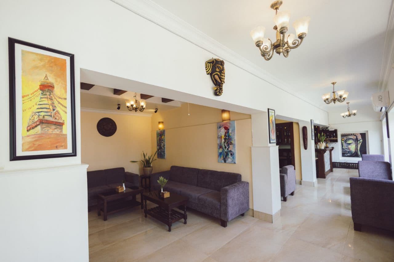 Un vestíbulo de hotel con mostrador de recepción, zona de estar y obras de arte en las paredes.