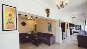 Un vestíbulo de hotel con mostrador de recepción, zona de estar y obras de arte en las paredes.