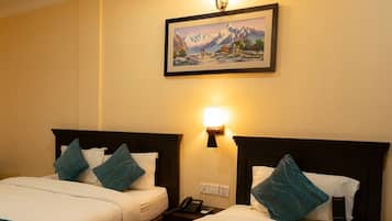 Habitación de hotel con dos camas, un cuadro en la pared, una lámpara de noche y un teléfono en la mesita.