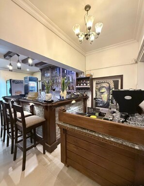 A bar area with wooden bar stools, a chandelier, and a large painting on the wall.