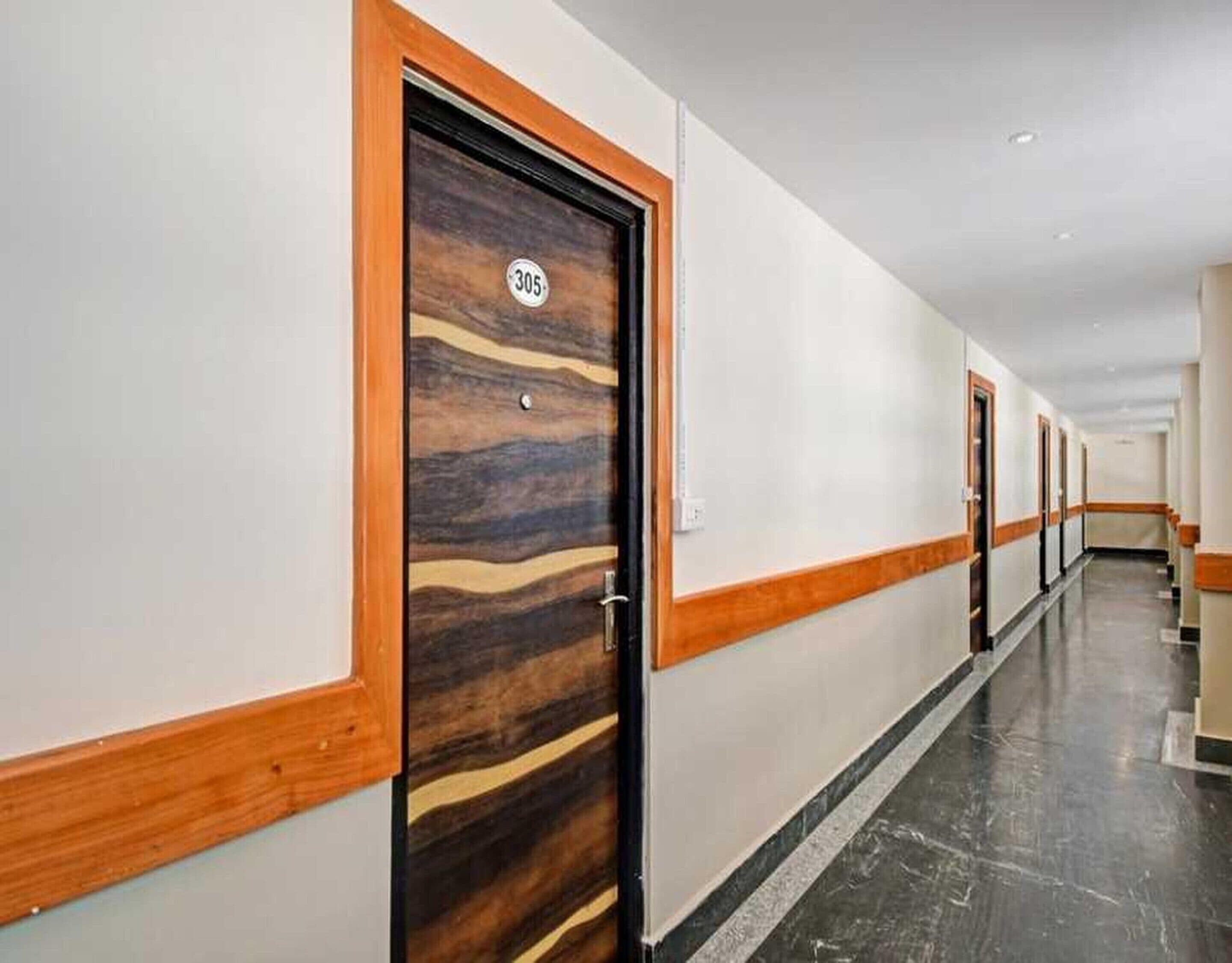 Pasillo de hotel con puertas de madera, número 305, y suelo de mármol.