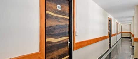 A hotel corridor with wooden doors, numbered 305, and a marble floor.