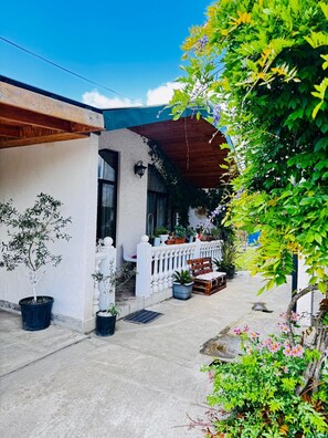 A house with a white exterior, a wooden porch, and potted plants.