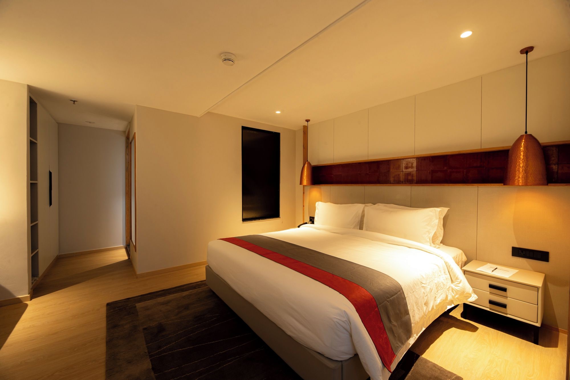 A modern bedroom with a large bed, bedside tables, and a built-in wardrobe.