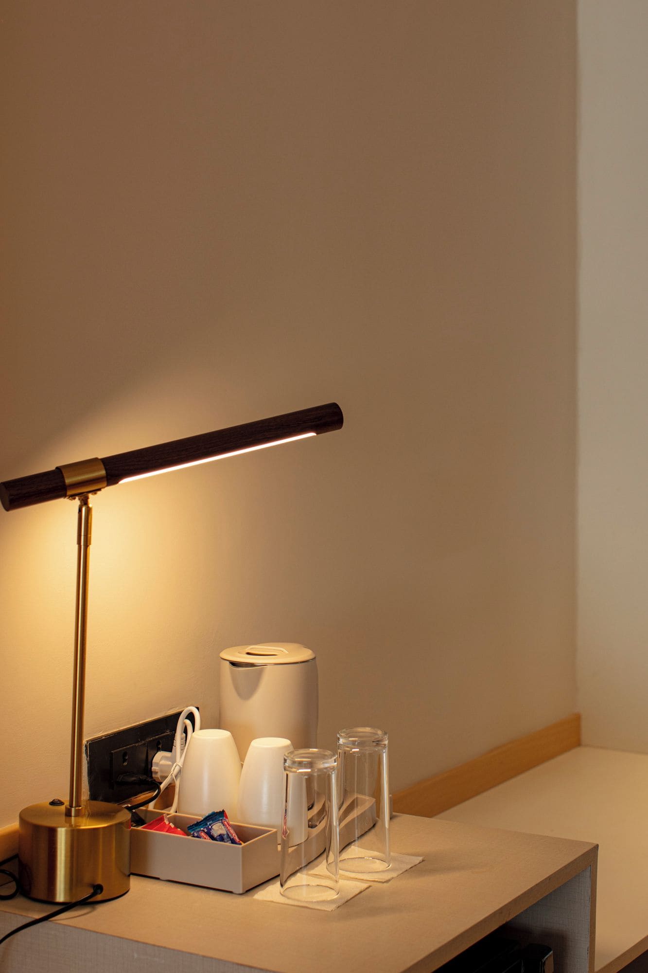 A desk with a desk lamp, a white cup holder, and a container with various items.