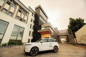 A white car parked in front of a modern building with a sign that reads 'The Inn.'
