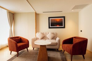 A modern living room with a sofa, two armchairs, a coffee table, and a framed picture on the wall.