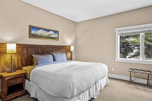 A bedroom with a large bed, two bedside lamps, a nightstand, a window with a view, and a framed picture on the wall. - The ‘106’ by Fern James
Adventure Awaits! (Canmore)