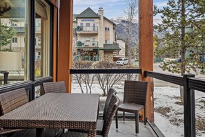 Ein Balkon mit Korbmöbeln, der auf eine verschneite Landschaft und ein Gebäude mit Steinaußenwand blickt.