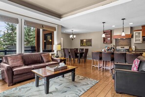 A spacious living area with a leather sofa, dining table, and chairs, a kitchen with modern appliances, and large windows offering a view of the outdoors. - The ‘106’ by Fern James
Adventure Awaits! (Canmore)