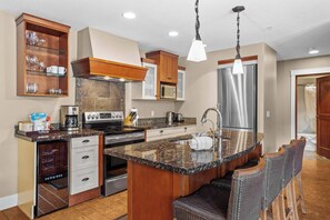 A kitchen with a central island, stainless steel appliances, wooden cabinetry, and a built-in microwave. - The ‘106’ by Fern James
Adventure Awaits! (Canmore)