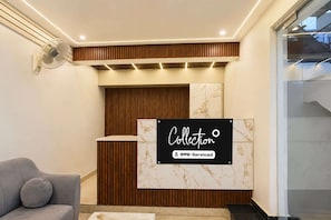 Un área de recepción con pared de mármol, diseño de paneles de madera y un letrero que indica que es administrado por OYO.