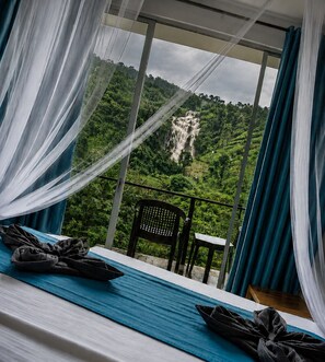 Una habitación con cama, una silla y vistas a una cascada.