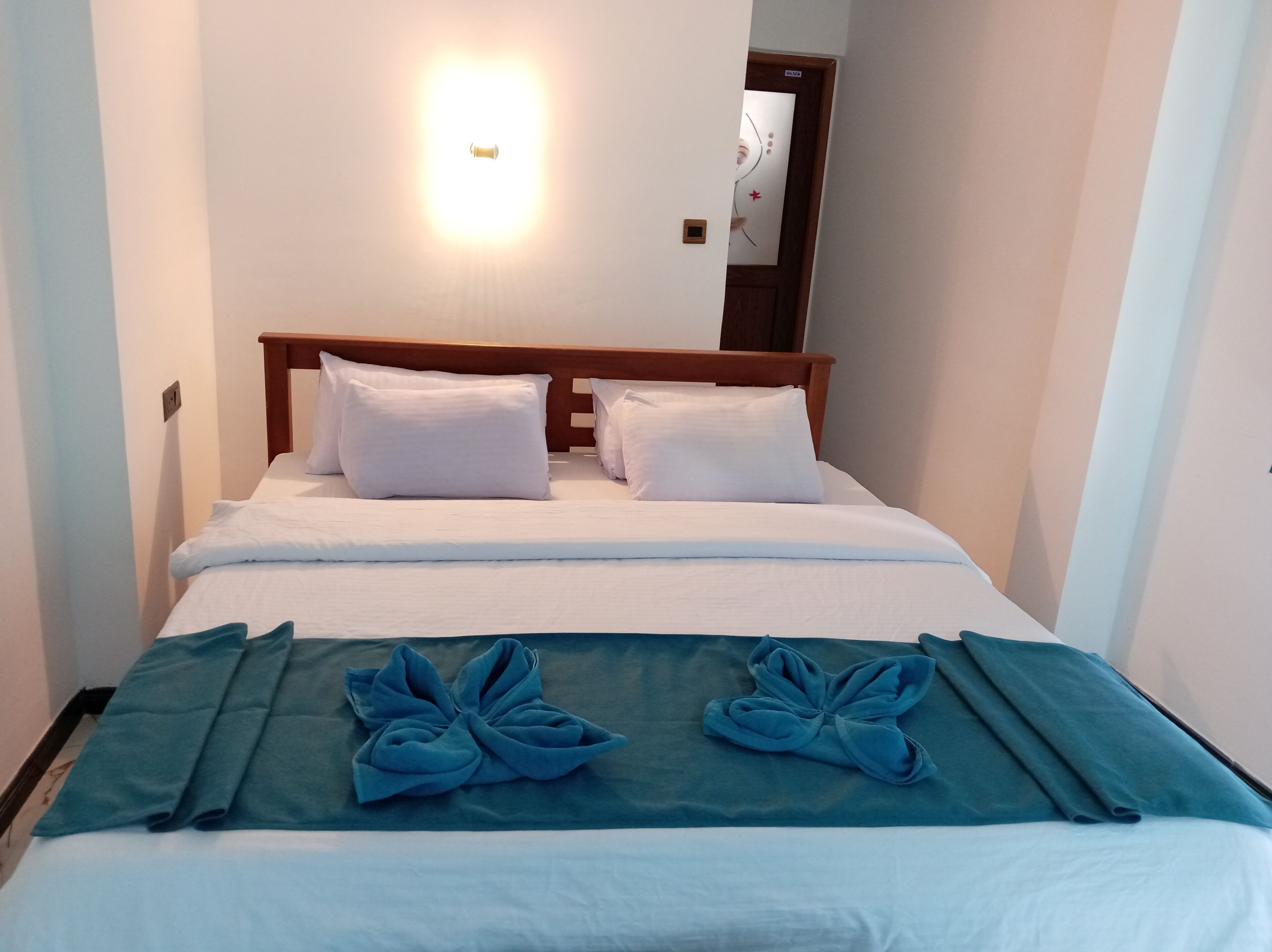 A hotel room with a bed, two pillows, a bedside table, and a mirror on the wall.