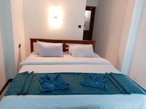 Habitación de hotel con cama, dos almohadas, mesita de noche y espejo en la pared.