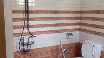 A bathroom with a shower, toilet, and a wooden floor.