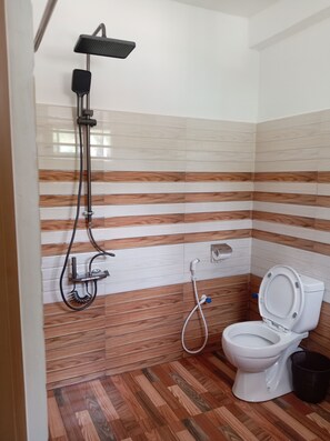 Un baño con ducha, inodoro y piso de madera.