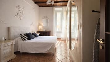 A bedroom with a large bed, a nightstand, a dresser, a mirror, and a door with a patterned curtain.