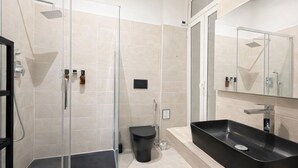 A modern bathroom with a glass-enclosed shower, a black sink, and a mirror above the sink. - BORGO APARTMENT IMPERO VATICANO (Roma)