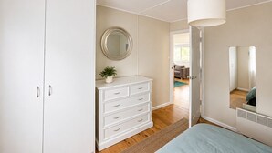 Ein Schlafzimmer mit einem Bett, einem Schminktisch, einem Spiegel und einer Tür zu einem weiteren Raum.