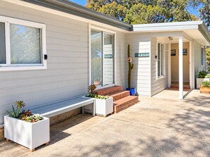 A modern house with a covered porch, a bench, and potted plants. - Wirani on the Water (Sanctuary Point)