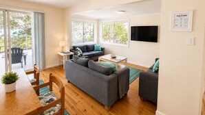Ein modernes Wohnzimmer mit einer Couch, einem Couchtisch und einem an der Wand befestigten Fernseher.