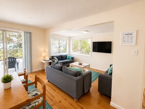 Ein modernes Wohnzimmer mit einer Couch, einem Couchtisch und einem an der Wand befestigten Fernseher.