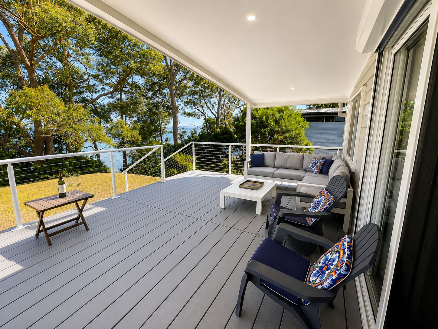 Une terrasse extérieure couverte, aménagée avec un canapé, des fauteuils et une table.
