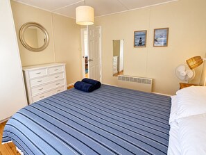 A bedroom with a bed, a dresser, a mirror, a radiator, and two wall-mounted lamps. - Wirani on the Water (Sanctuary Point)