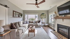 A living room with a sectional sofa, a fireplace, a television, and a ceiling fan. - Family Home, Hot Tub, Near Whiskey Row (Prescott)