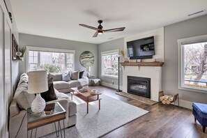 Un salon avec une cheminée, un téléviseur et un ventilateur de plafond.