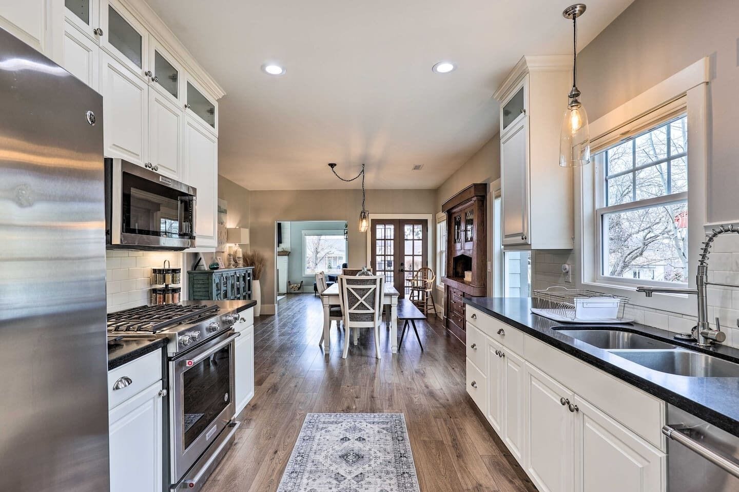 A modern kitchen with stainless steel appliances, white cabinetry, and a large window providing natural light.