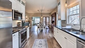 A modern kitchen with stainless steel appliances, white cabinetry, and a large window providing natural light. - Family Home, Hot Tub, Near Whiskey Row (Prescott)