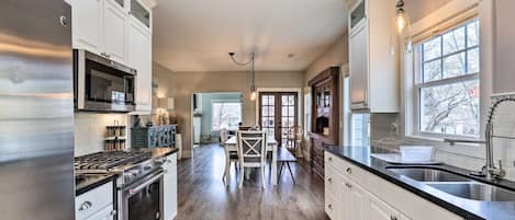 A modern kitchen with stainless steel appliances, white cabinetry, and a large window providing natural light.
