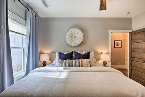 Une chambre avec un grand lit, deux tables de chevet, un élément de décoration circulaire fixé au mur, et une porte donnant sur une autre pièce.