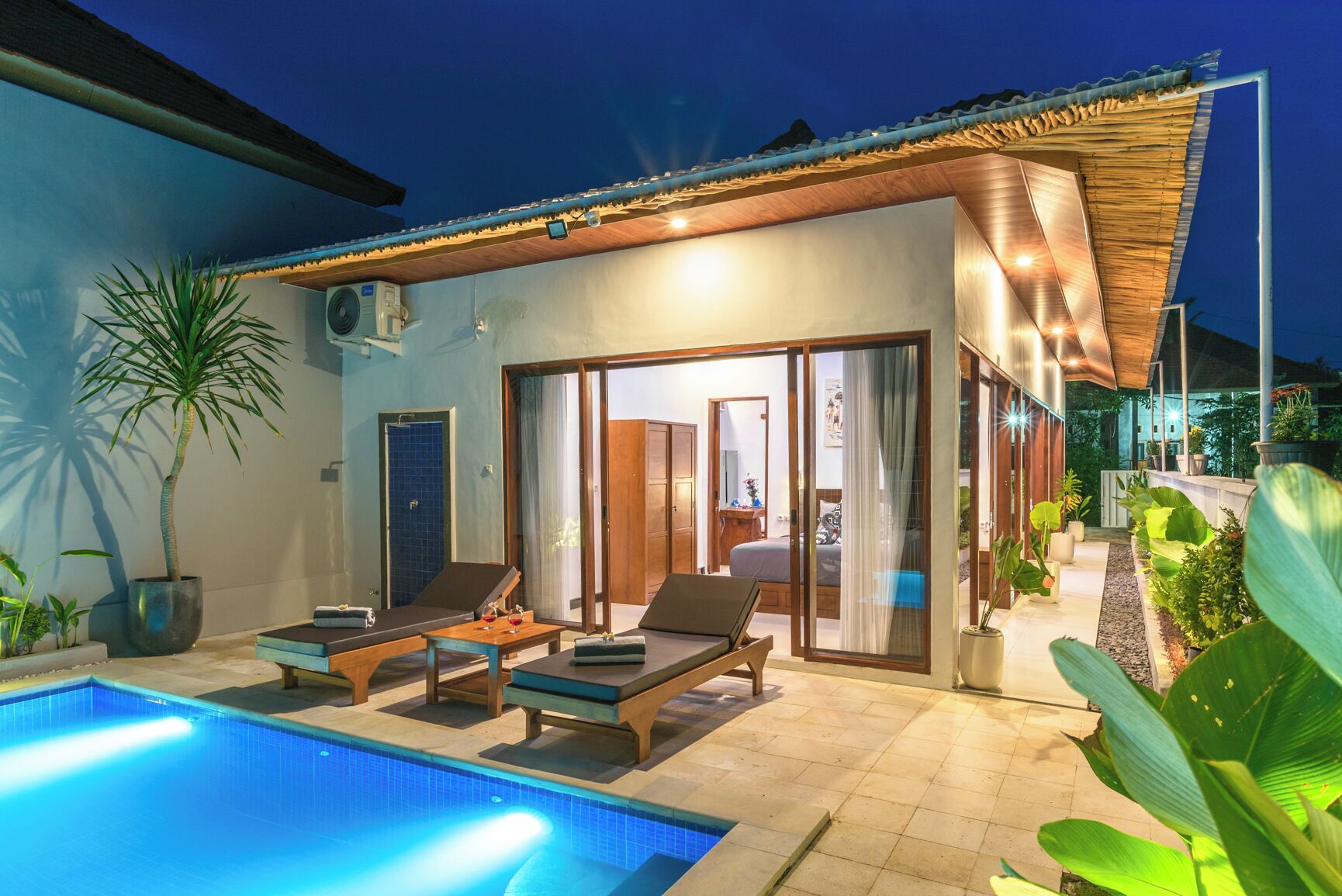 Eine moderne Villa mit Swimmingpool, Liegestühlen und einer überdachten Terrasse.