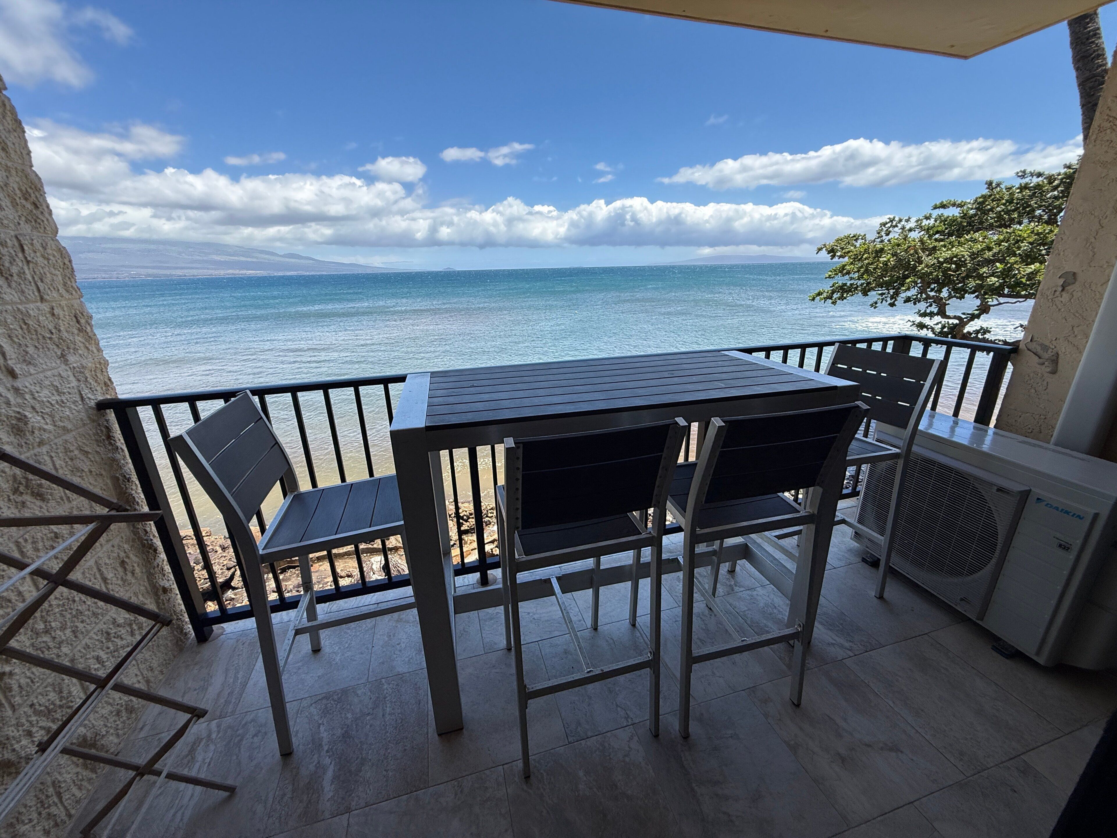 Un balcón con mesa y sillas con vistas al mar.