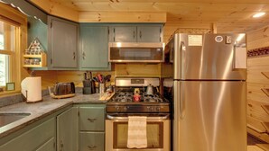 Eine Küche mit Holzschränken, einem Edelstahlkühlschrank, einer Mikrowelle und einem Herd.