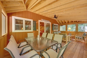 A wooden interior with a dining table and chairs, large windows, and a ceiling fan. - North Conway: Updated 3BR Cabin Sleeps 9, Fire Pit (North Conway)