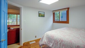 Un dormitorio con cama, ventana, puerta y una lámpara en el techo.